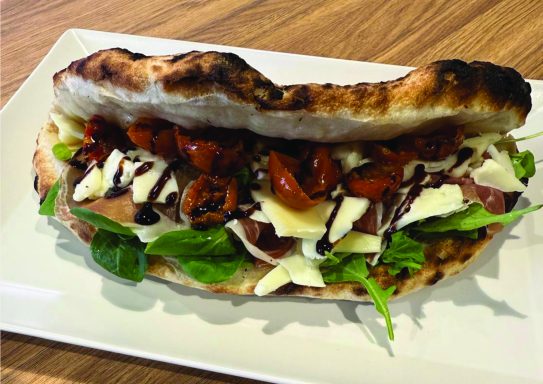 panuozzo ona Sandwich garni de légumes, viande, fromage et sauce sur pain grillé.