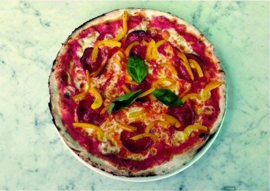 Pizza garnie de sauce tomate, pepperoni, poivrons jaunes et basilic frais.